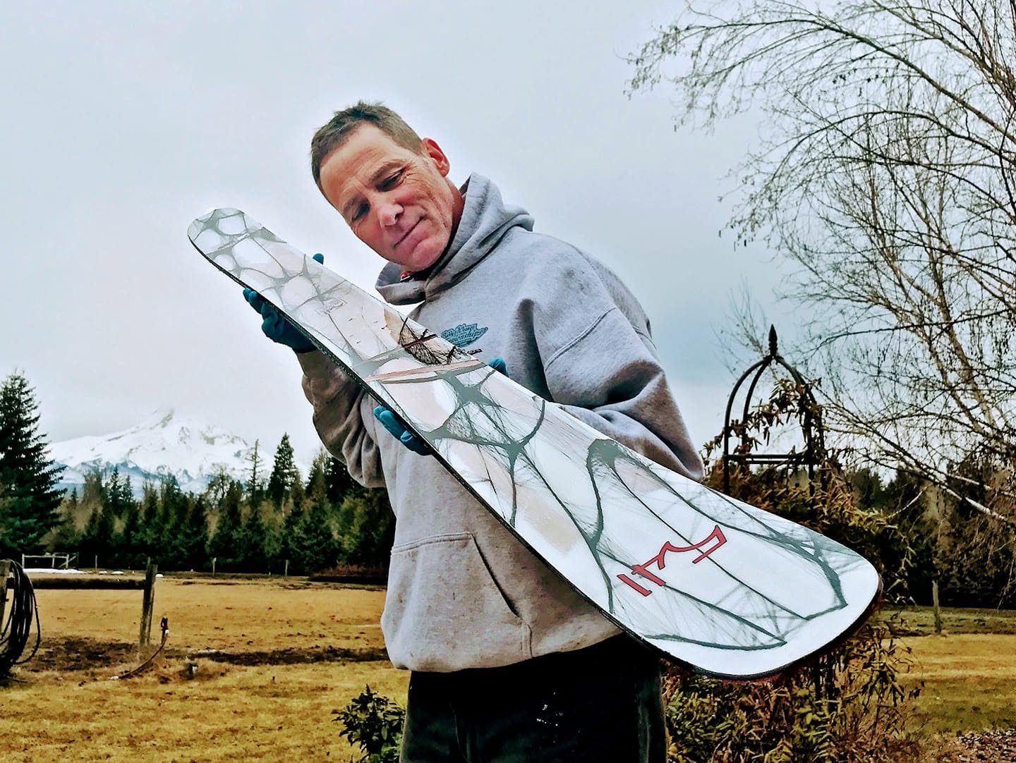 Jesse Scroggins looking over a 541 ski, with Mt. Hood behind